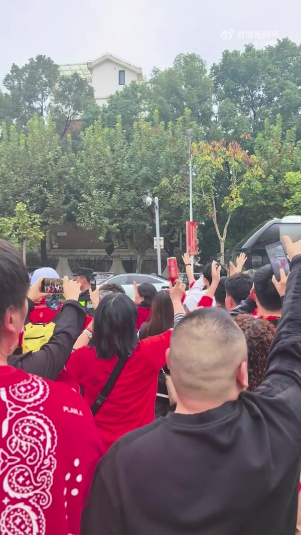 球迷夹道欢迎重庆铜梁龙球队大巴，并高举双手喊“重庆雄起！”